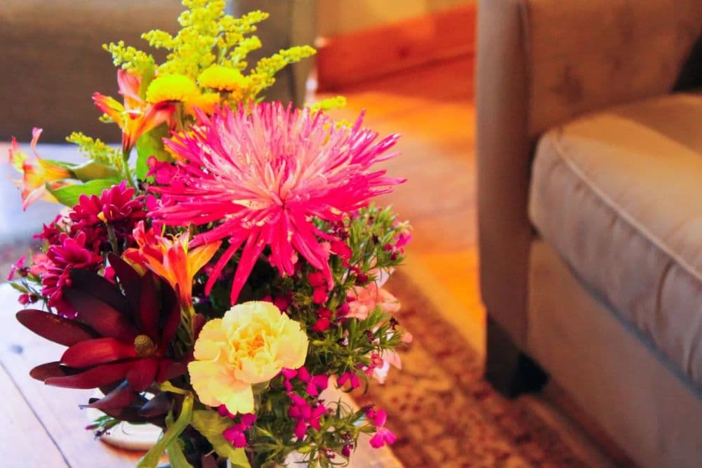 A vibrant bouquet of mixed flowers in a decorative vase on a wooden table.
