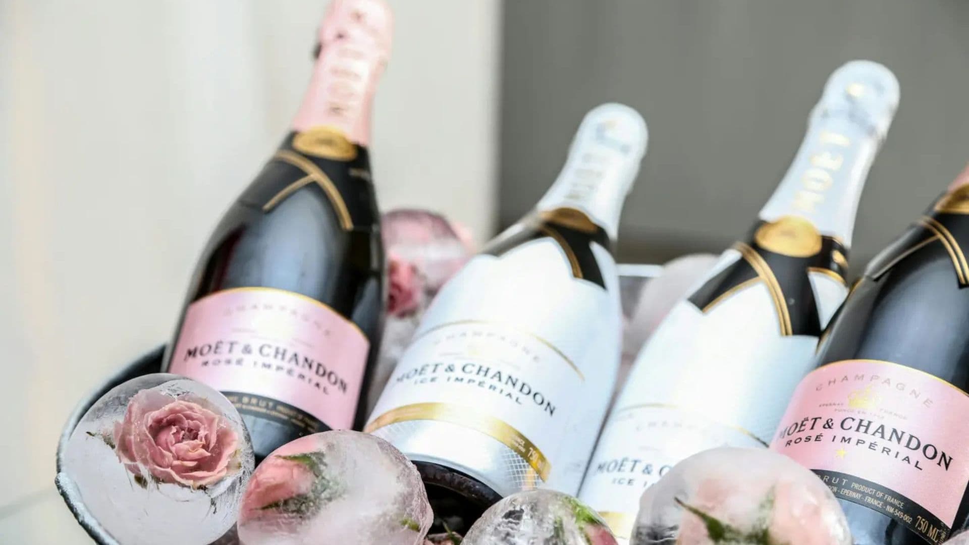 Three bottles of Moët & Chandon champagne are elegantly displayed in a bucket with ice and roses.