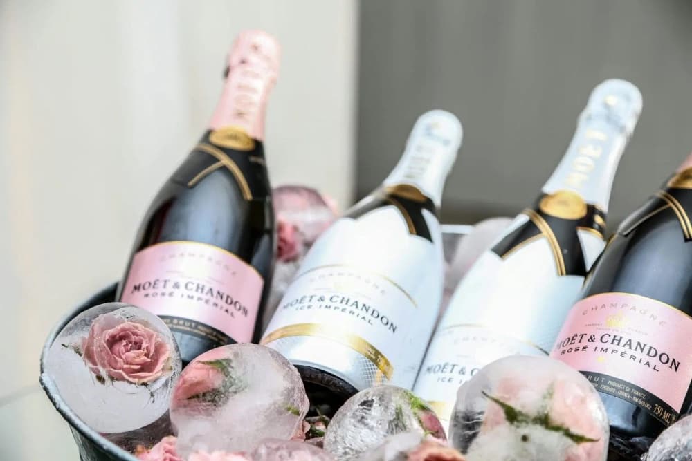 A chilled bucket filled with Moët & Chandon champagne bottles and ice, adorned with pink roses.