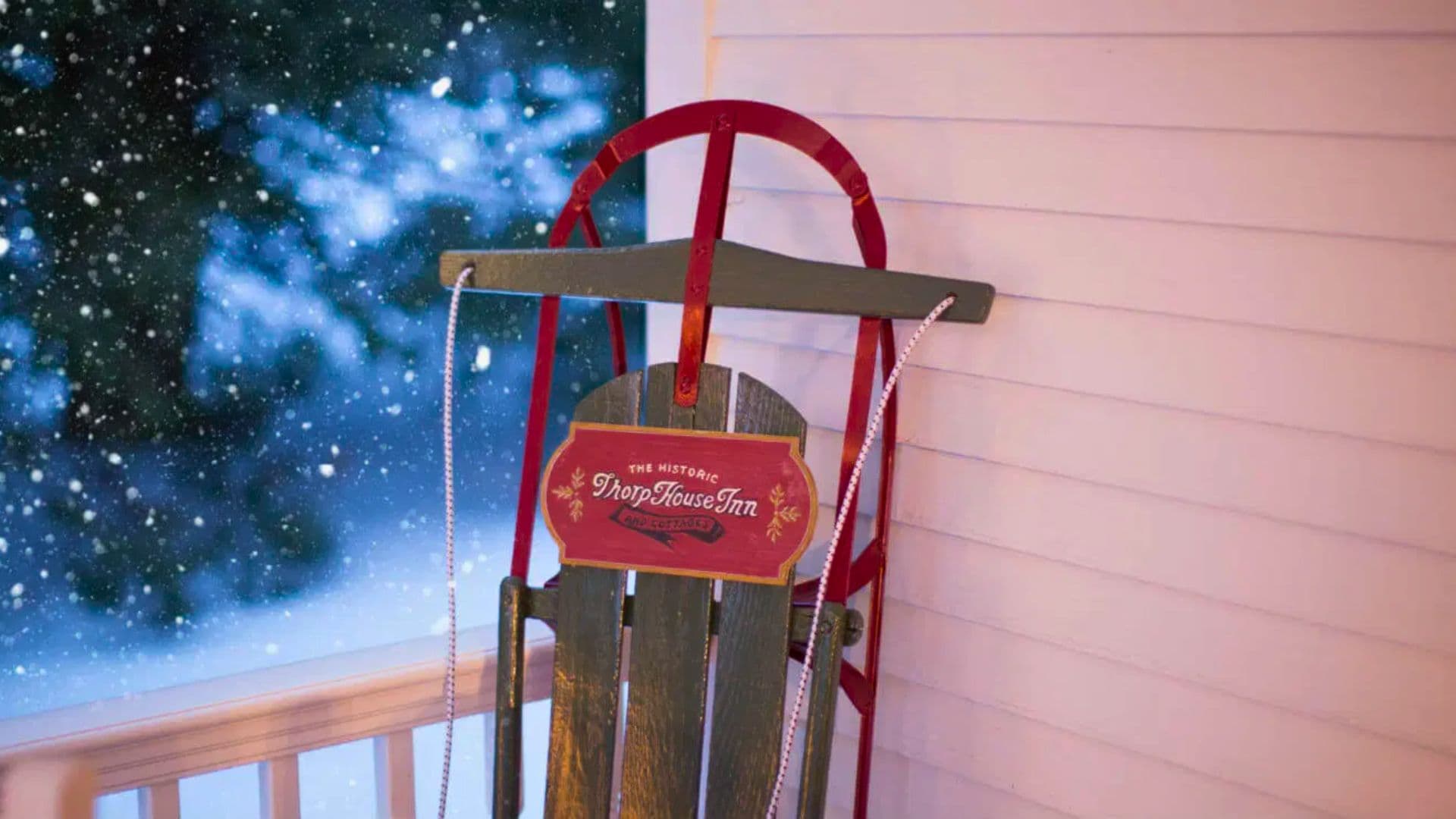 A wooden sled with a sign reading "The Historic Drop House Inn" against a snowy backdrop.