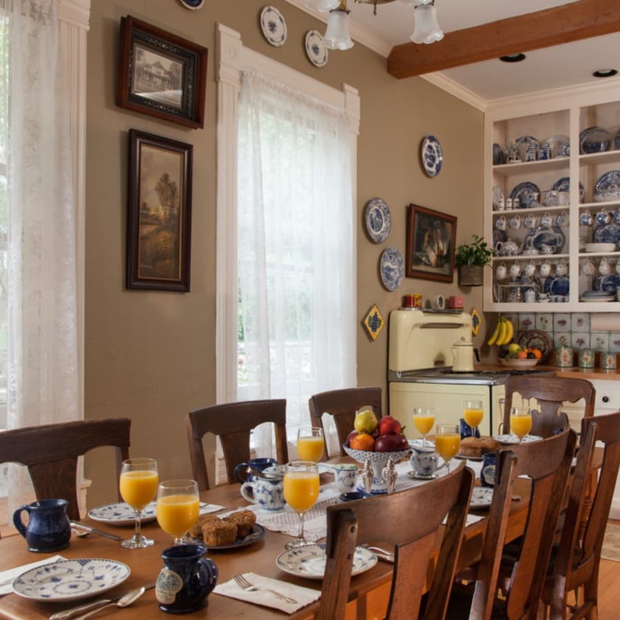 A cozy dining room set for breakfast with plates, glasses of orange juice, and an antique yellow stove.