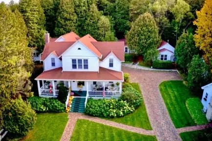Aerial view of a large white home with red roof and wrap around porch Aerial view of a large white home with red roof and wrap around porch