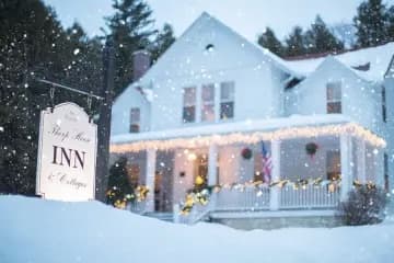 Large white home during winter with sparkling lights on the porch Large white home during winter with sparkling lights on the porch